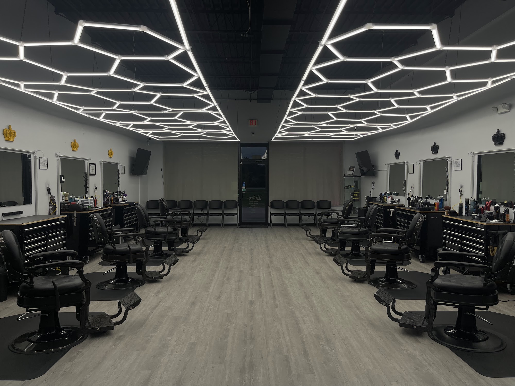 The inside of Royal Barber Studio: two rows of black barber chairs facing mirrored stations under hexagon ceiling lights